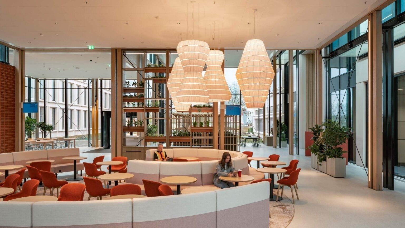 A lounge with round red sofas and paper pendant lamps
