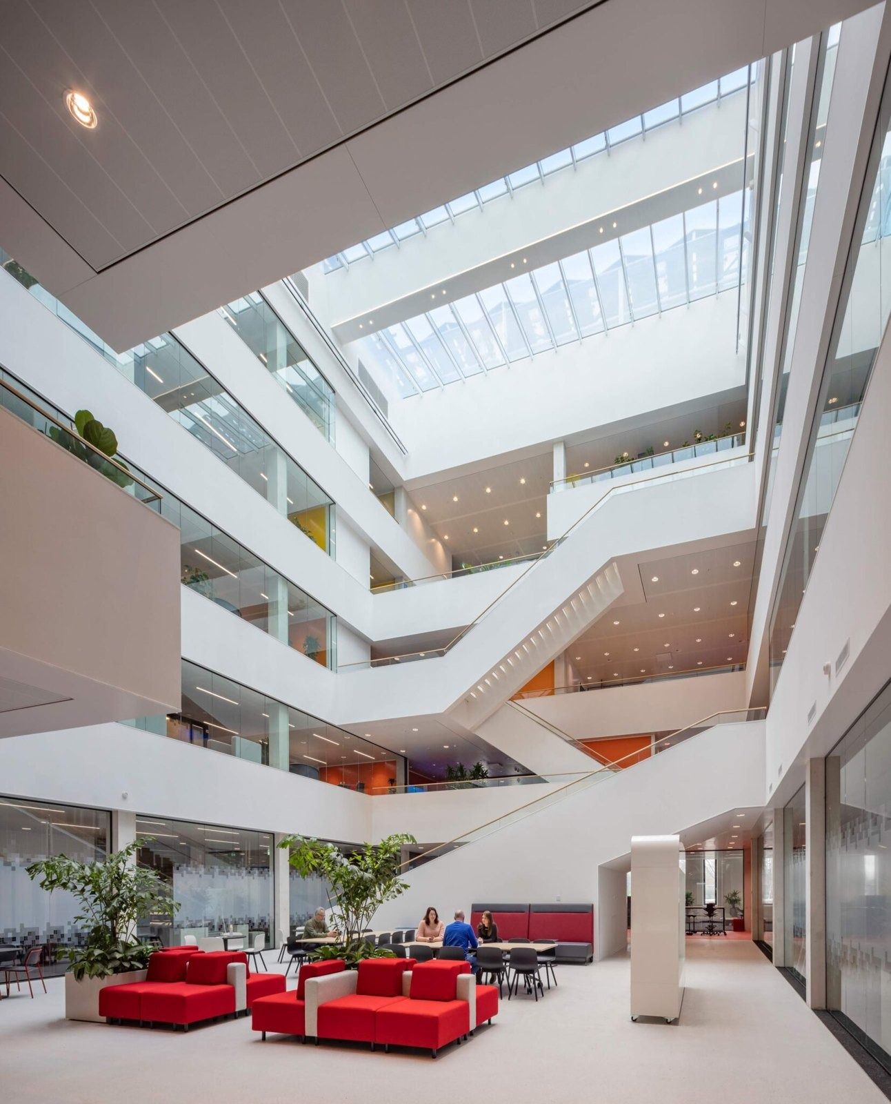 An atrium with white balconies and red sofas