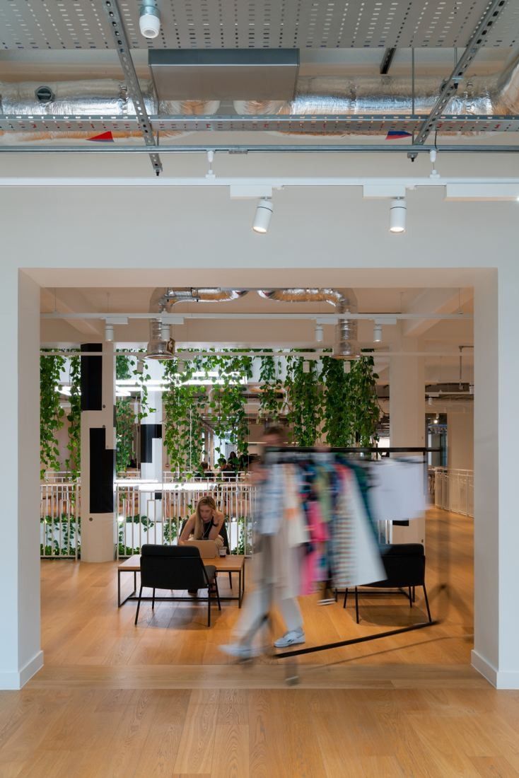 ASOS: Bright room with clothes rails and plants seen through a doorway