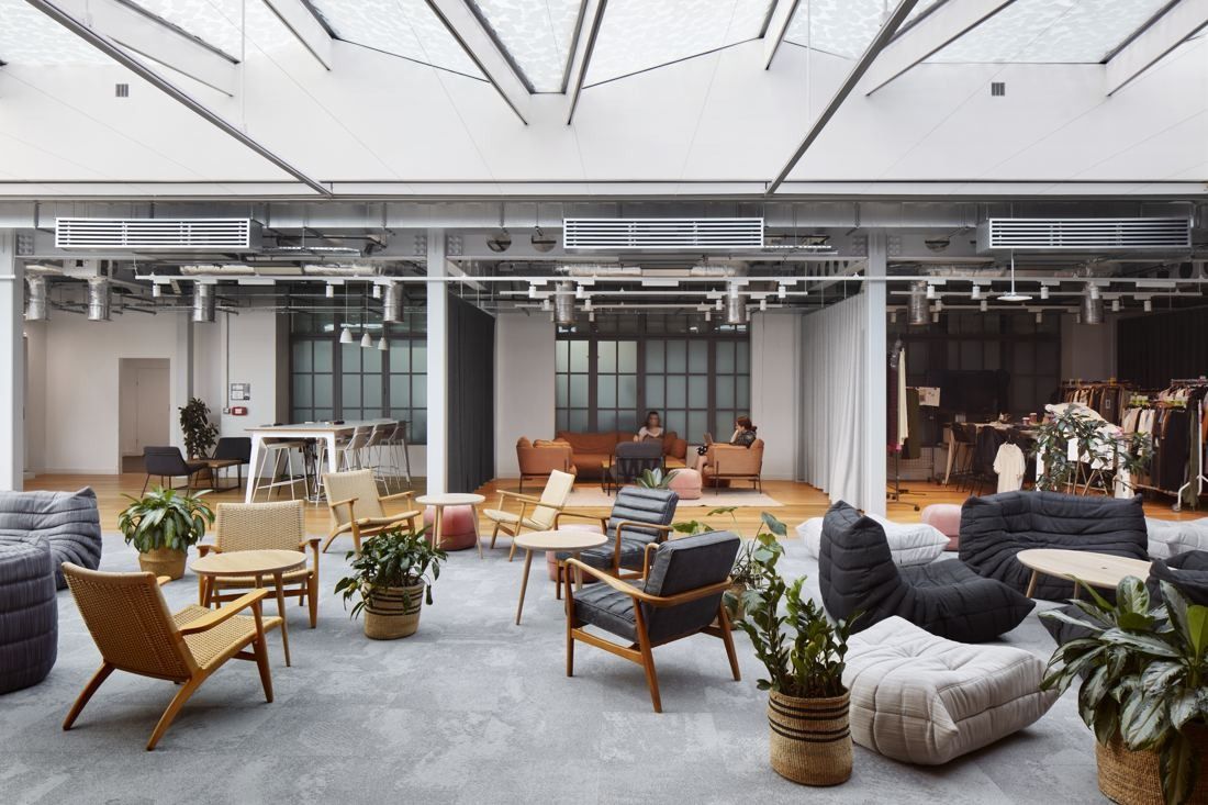 ASOS: Lounge with armchairs, low tables and plants under a glazed roof