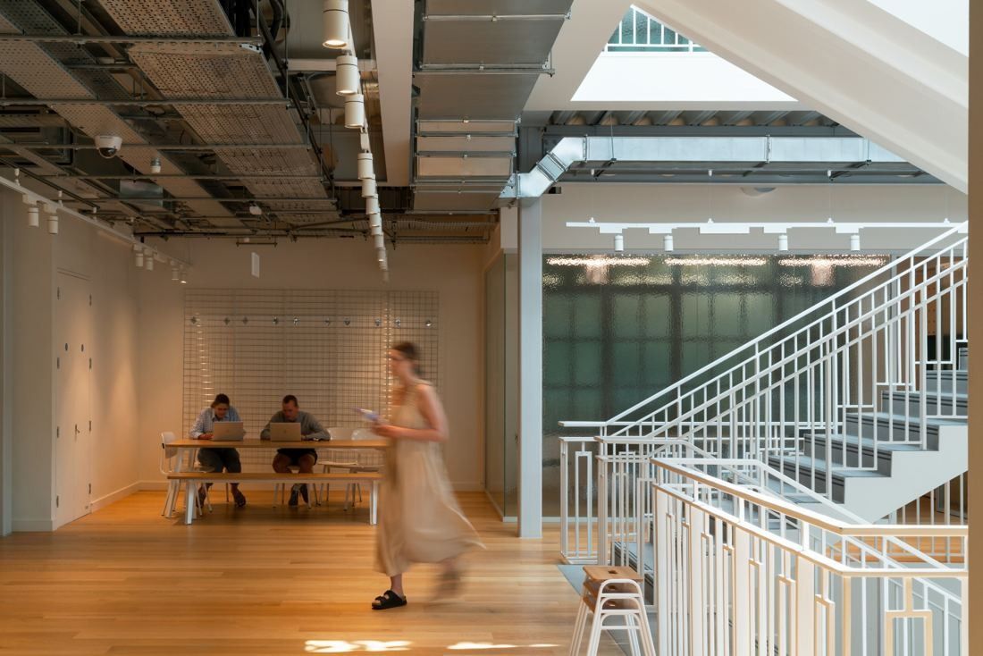 ASOS: Open room with a long table beside a white staircase with patterned railings