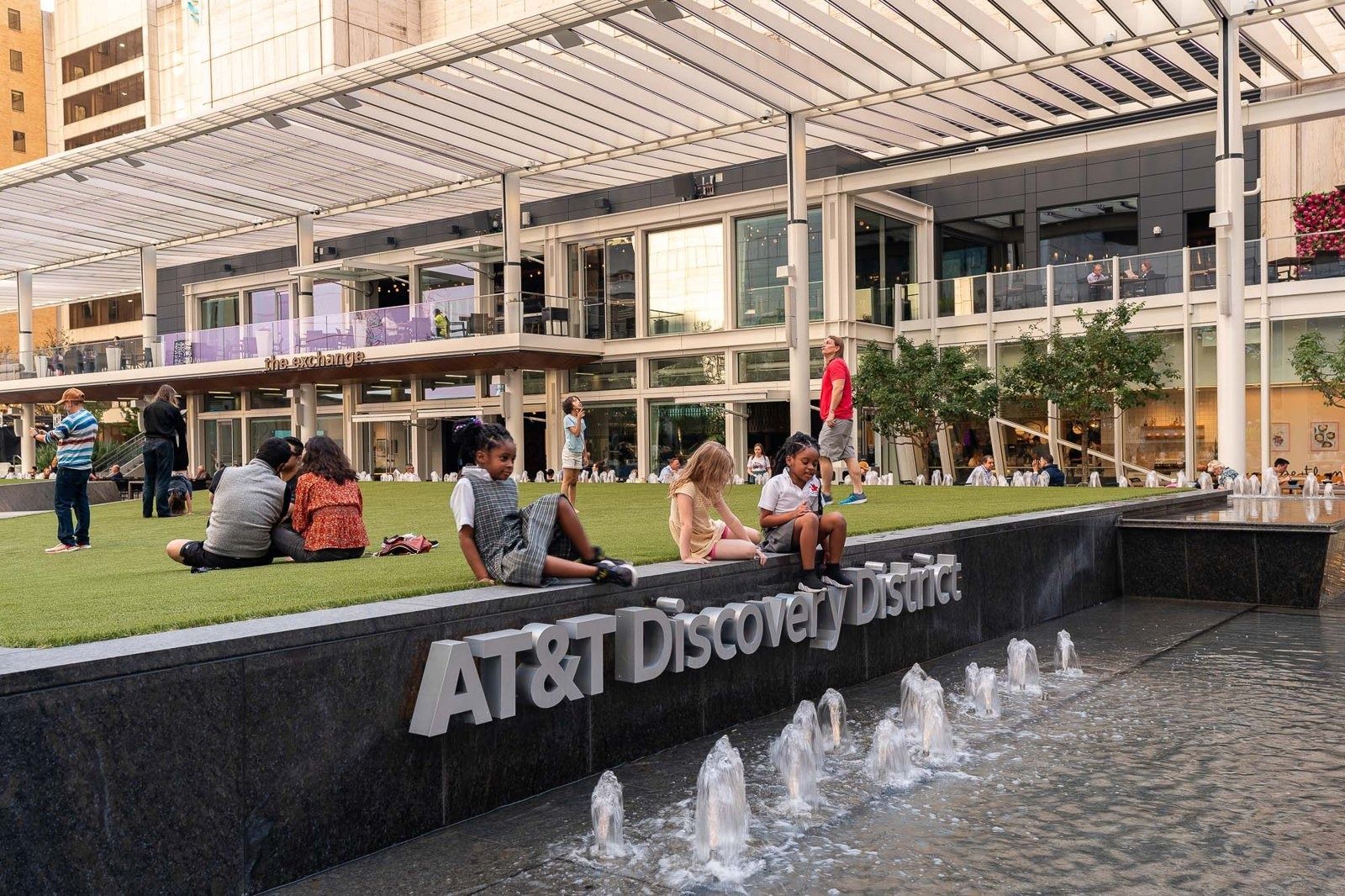 AT&T: Lawn with people relaxing behind a fountain sign
