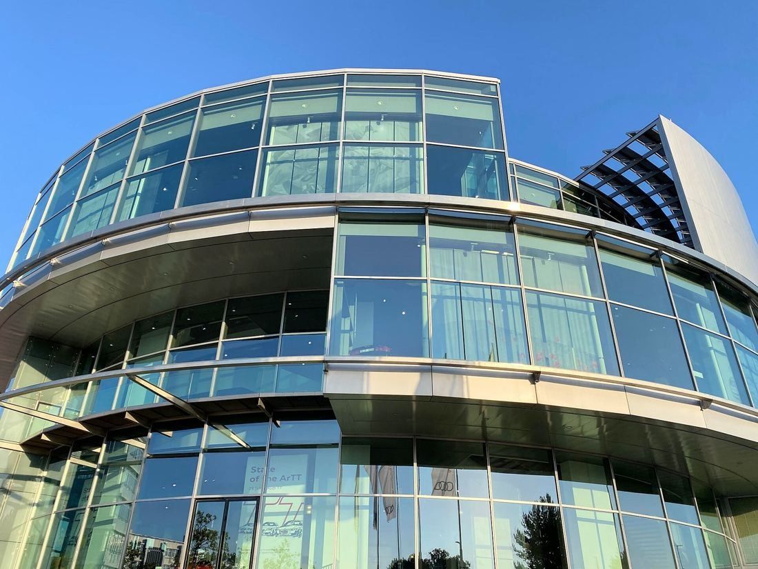 Audi: Curved glass facade seen from below against a clear sky