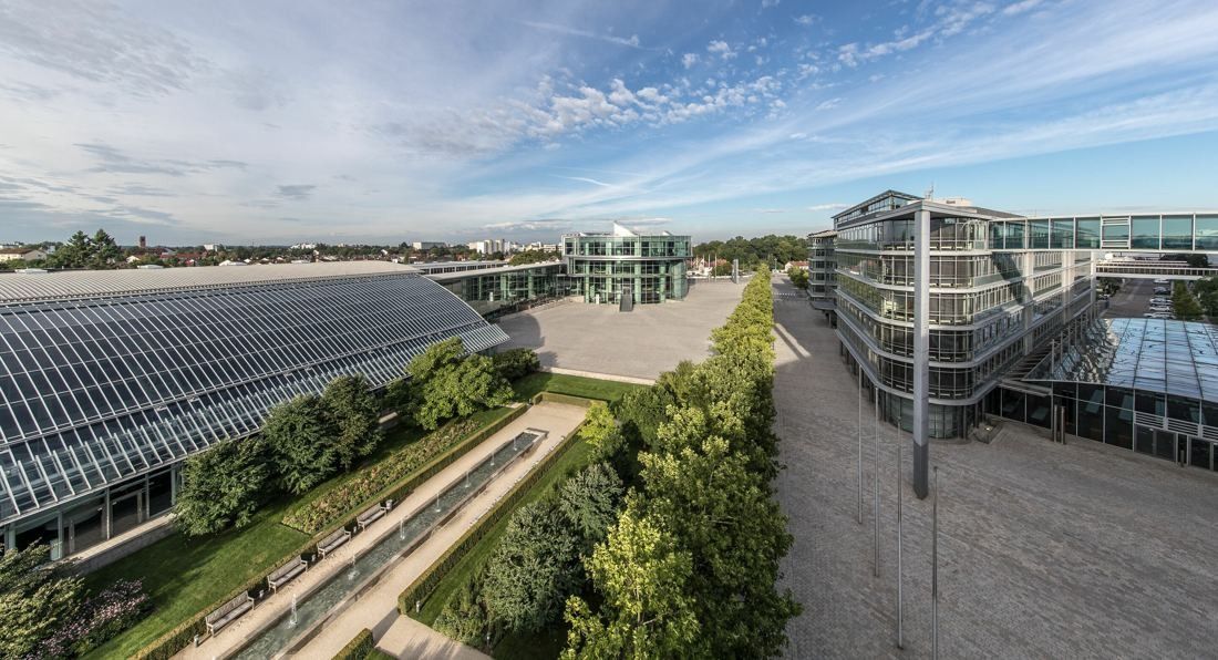 Audi: Elevated view over a long glass-roofed hall, trees and office buildings