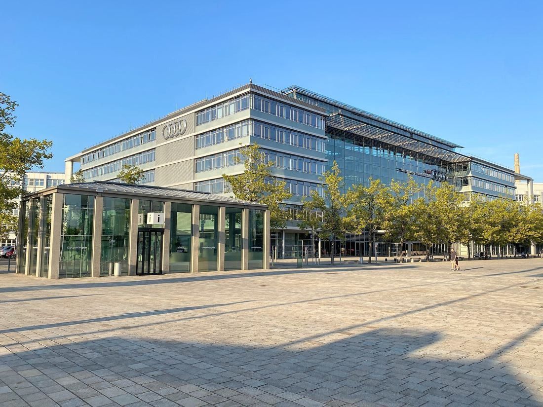 Audi: Glass pavilion in front of a multi-storey office building on a paved plaza