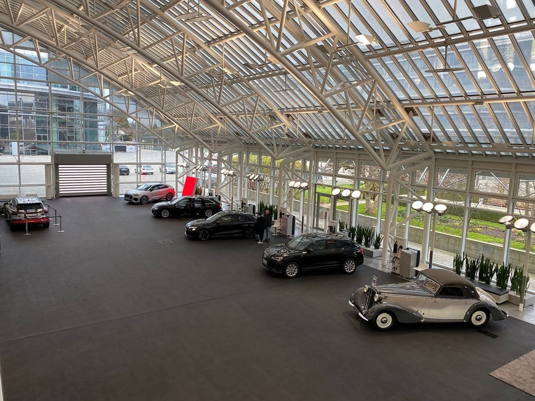Audi: Large hall with a white steel-and-glass roof, cars parked in a row on a dark floor