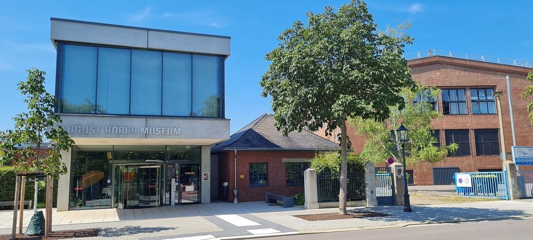 Modern glass-topped entrance building with older brick factory buildings on either side