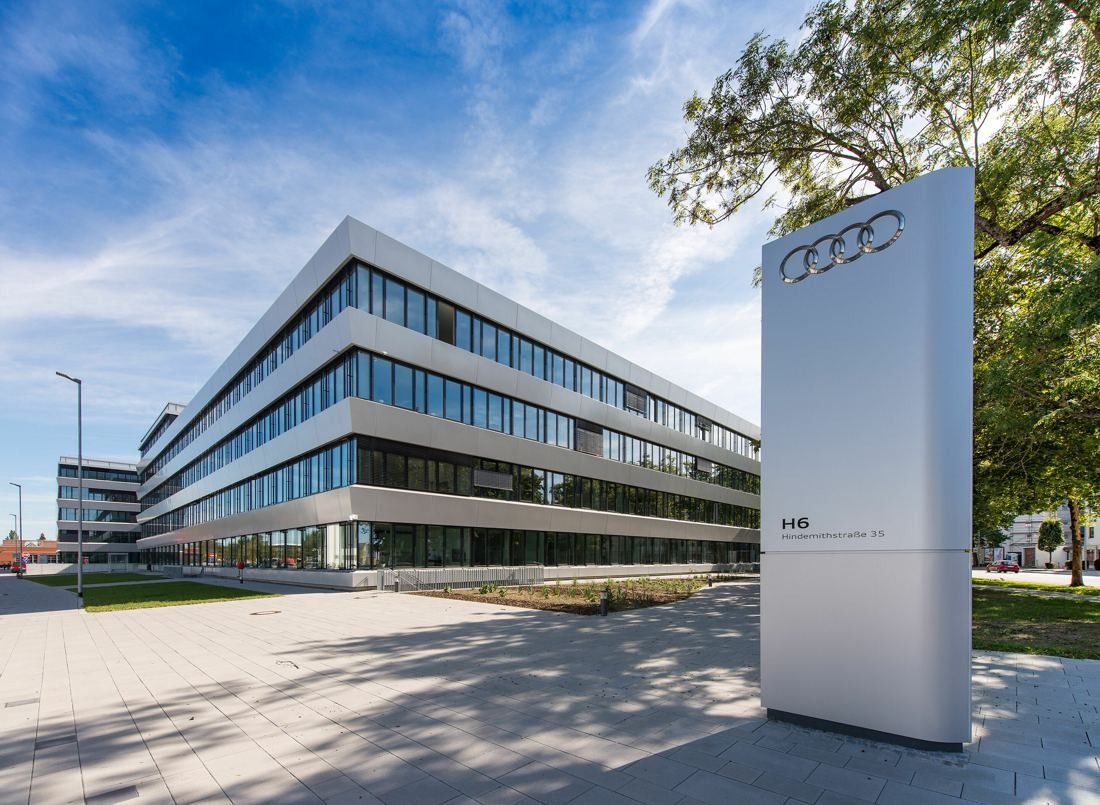 Audi: Office building with horizontal glass bands and a tall white sign with four rings in front