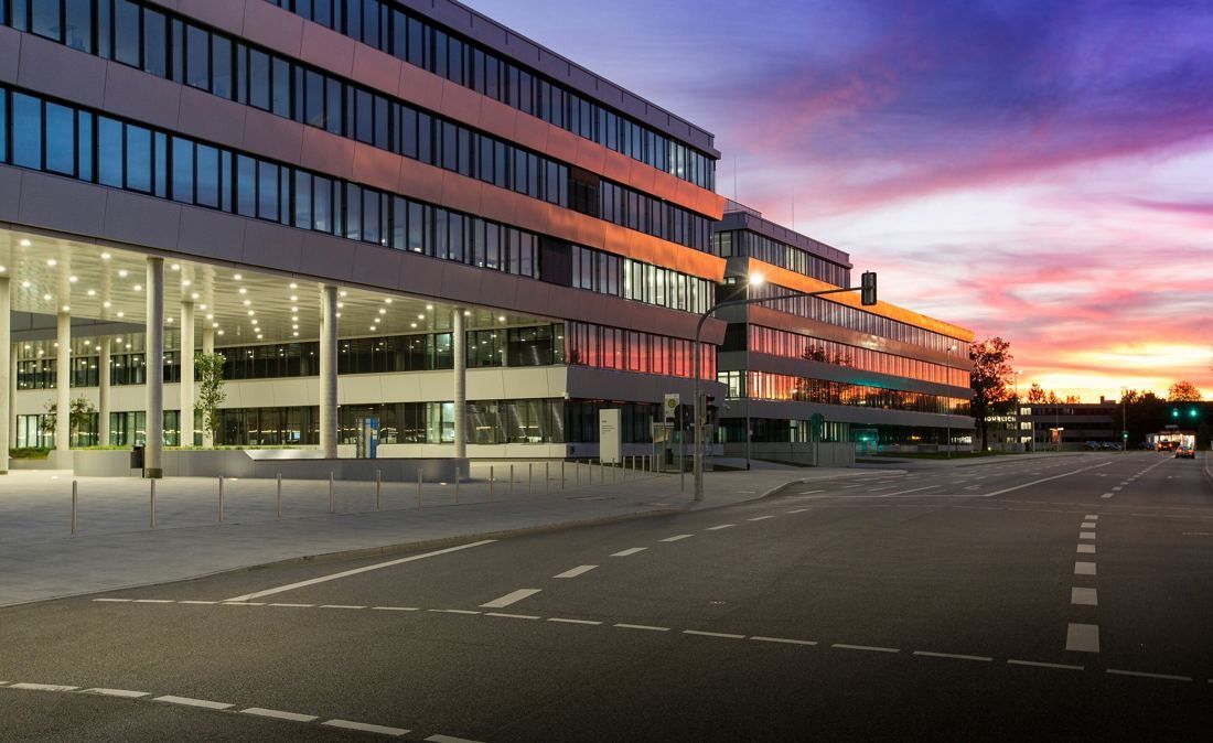 Audi: Office buildings along an empty road under a colourful sunset sky