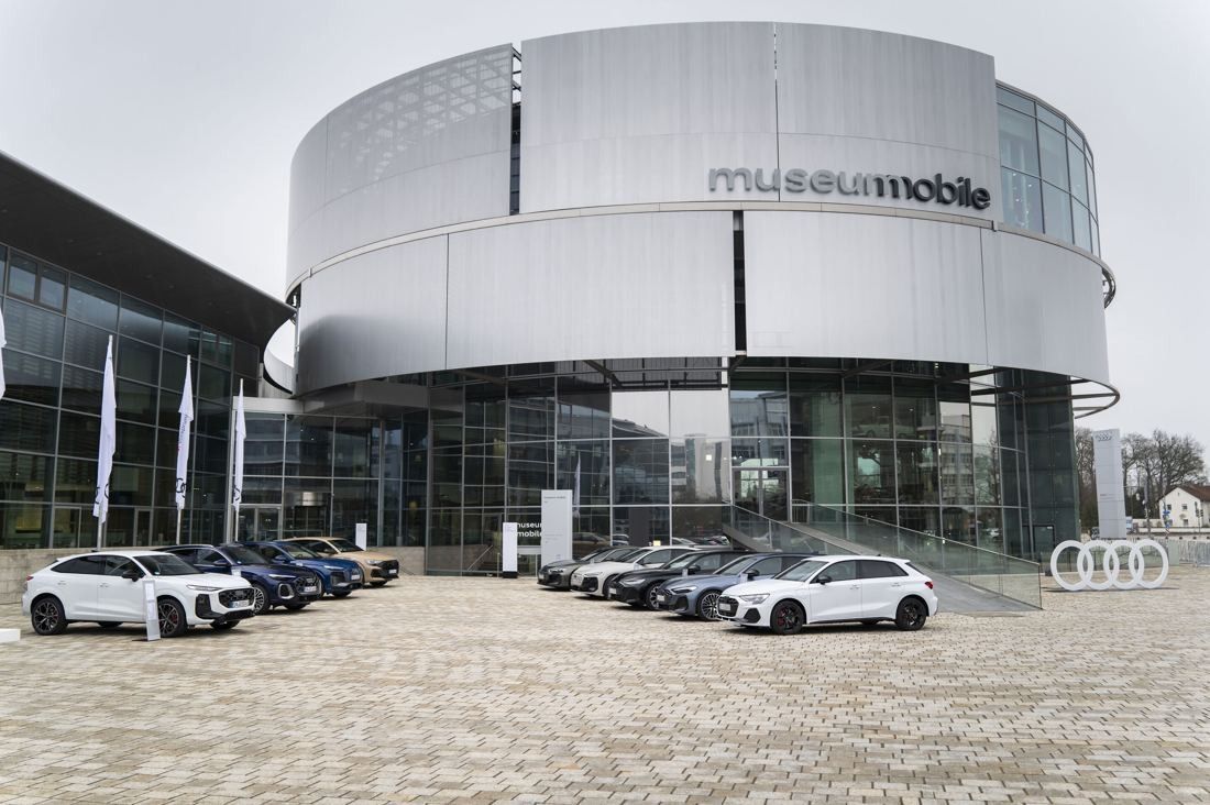 Audi: Silver drum-shaped building with museum mobile lettering above a glass ground floor, cars parked in front