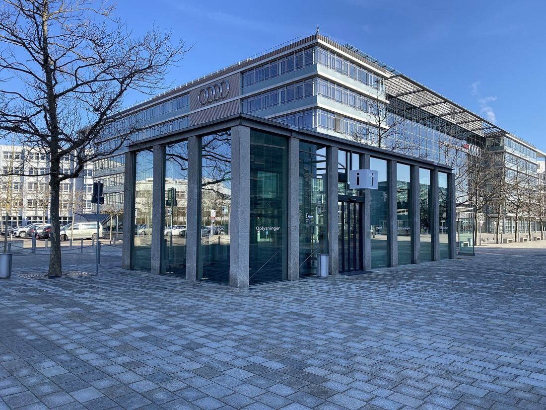Audi: Small glass pavilion with stone columns in front of a larger office building