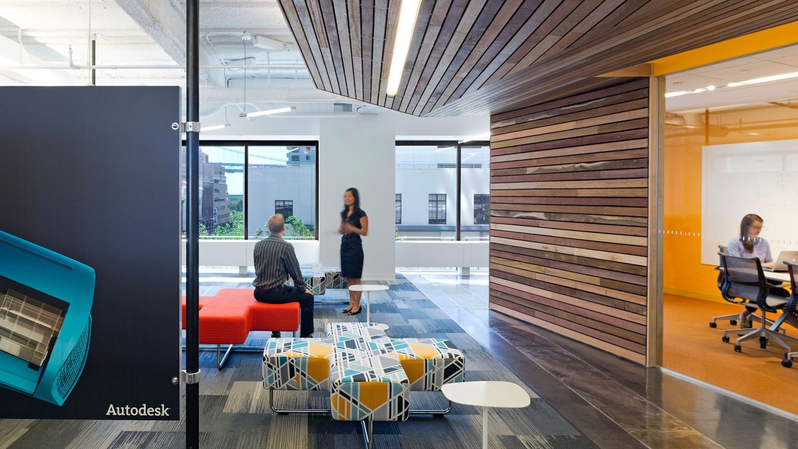 Autodesk: A lounge with red and patterned seats beside a timber wall