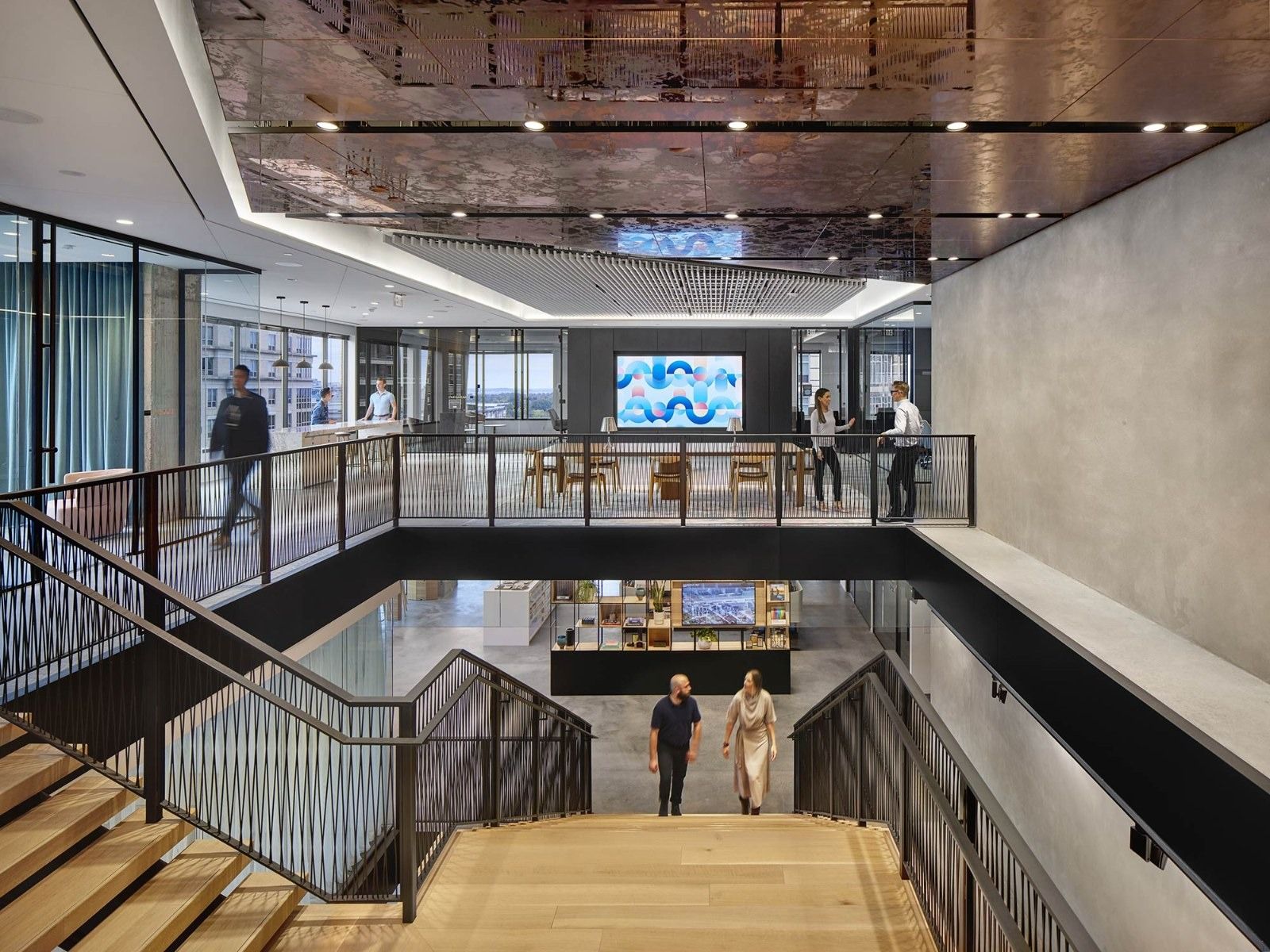 A grand stair with wooden treads dropping through an opening between floors