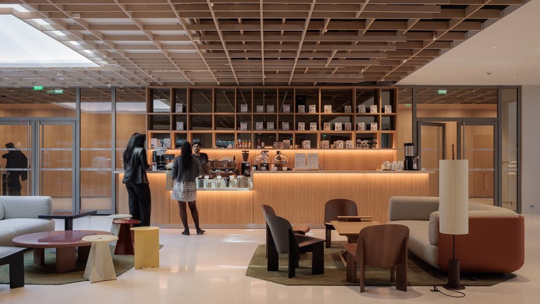 AXA: Coffee bar with wooden shelving, lounge chairs and sofas under a wooden lattice ceiling
