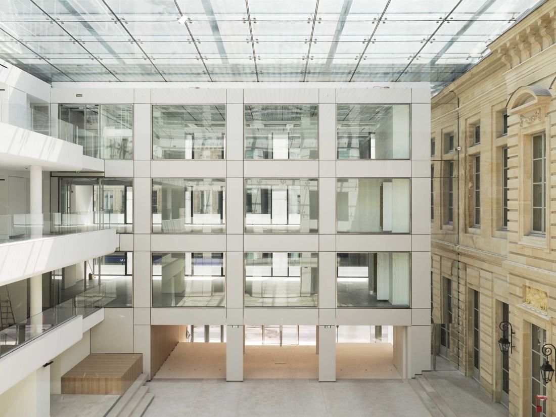 AXA: Glass-roofed courtyard between a historic stone façade and white office floors