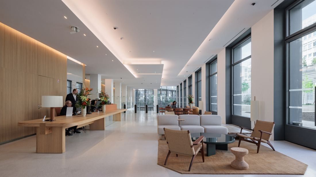 AXA: Long reception hall with a wooden desk, lounge seating and tall windows