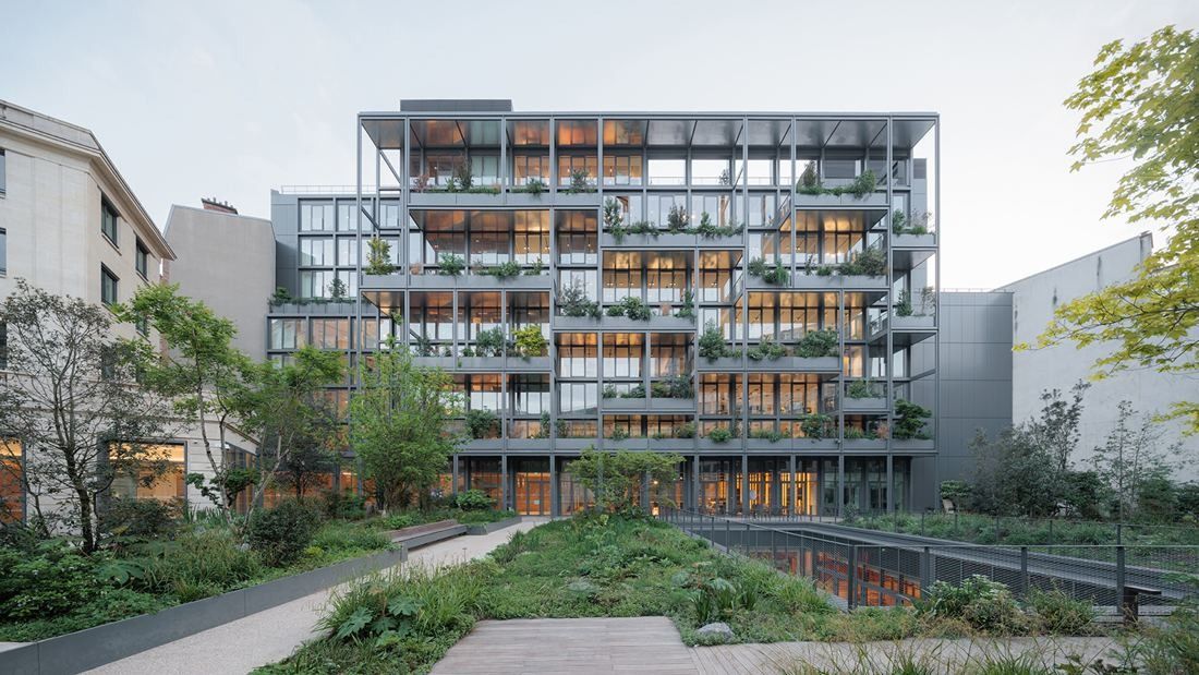 AXA: Office building with planted balconies on every floor seen across a garden path