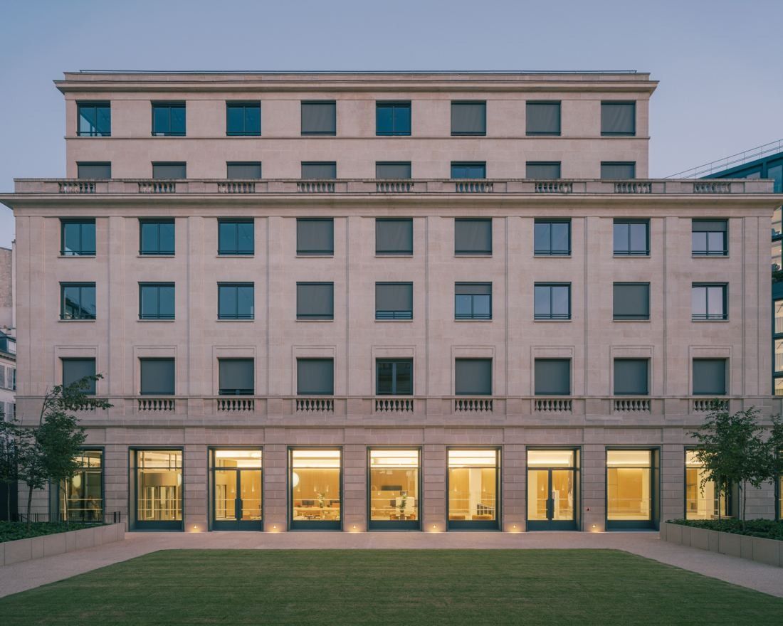 AXA: Pale stone office building with rows of windows facing a lawn