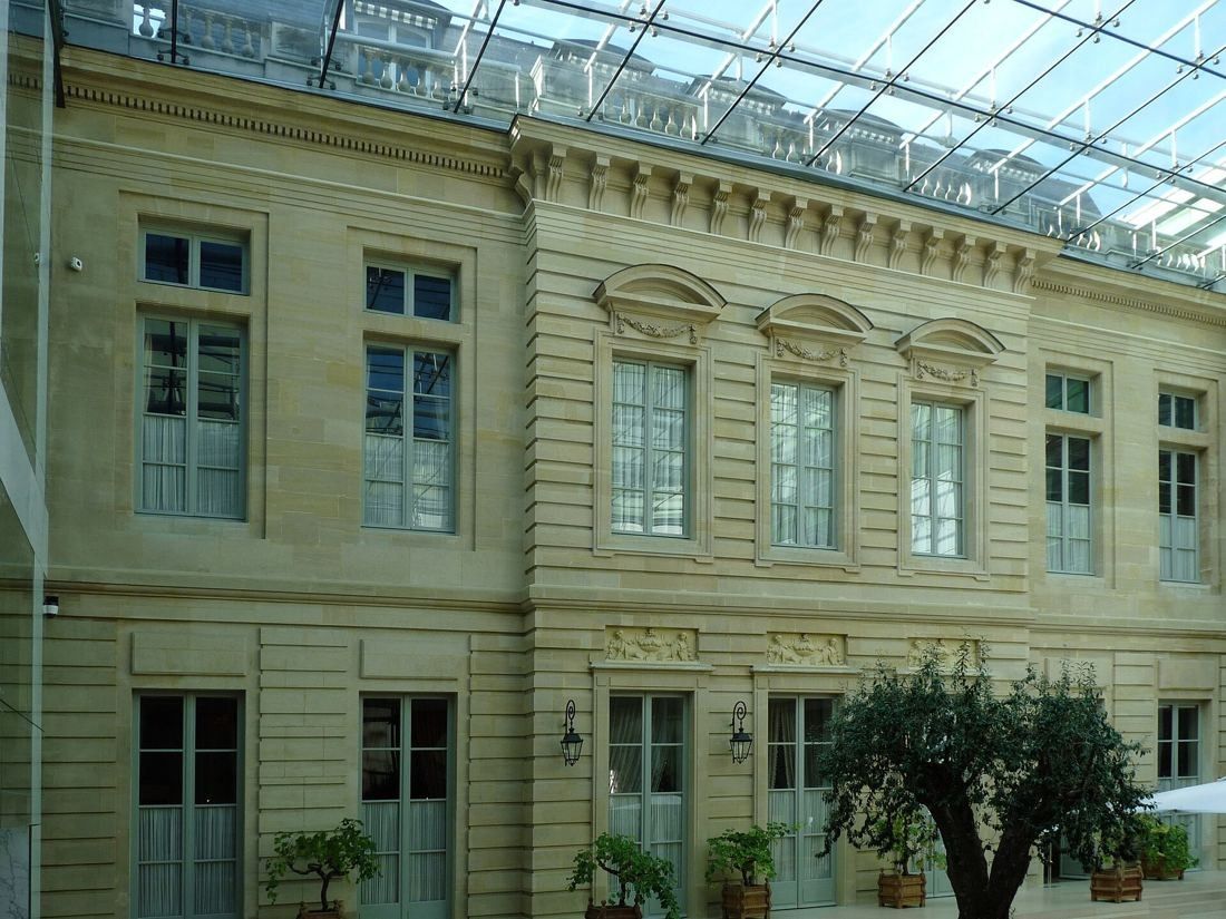 Stone mansion façade under a glass courtyard roof
