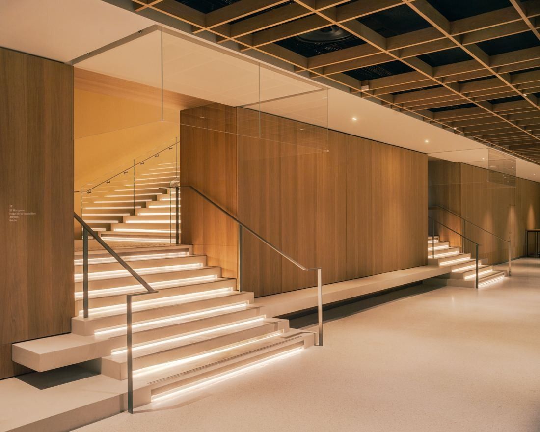 AXA: Wide lit staircase between wooden walls under a lattice ceiling