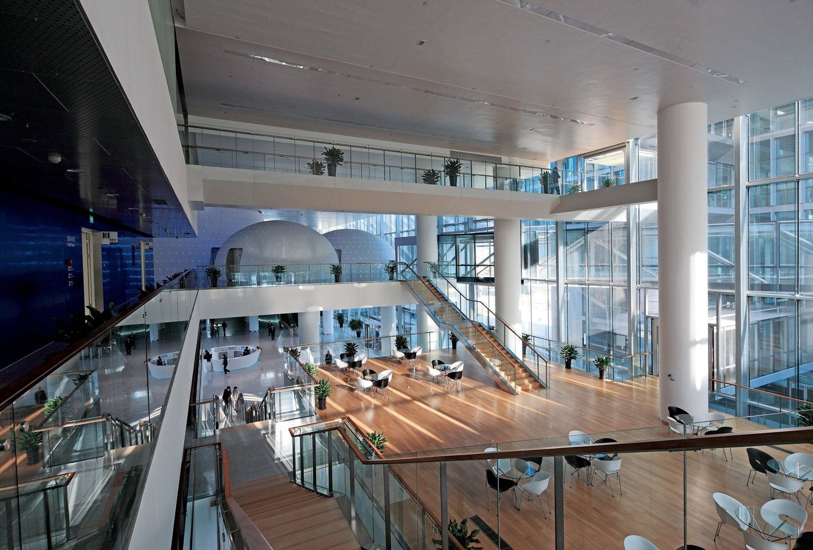 Baidu: Bright atrium with wooden floors, café tables, a staircase and two white domes