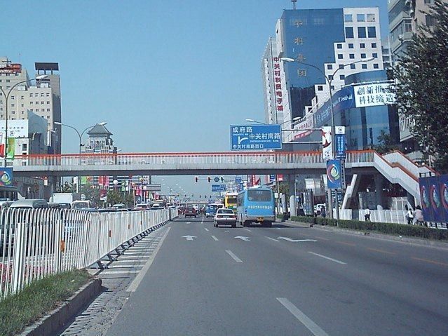 Wide road through Zhongguancun with office buildings and a footbridge