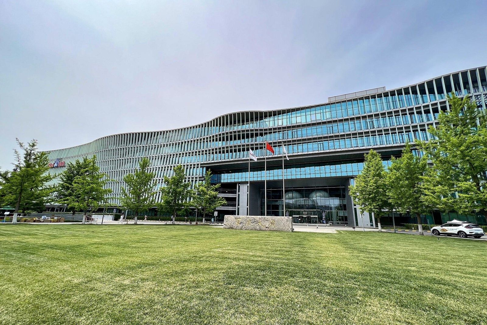 Baidu: Lawn in front of a curving glass building with flags
