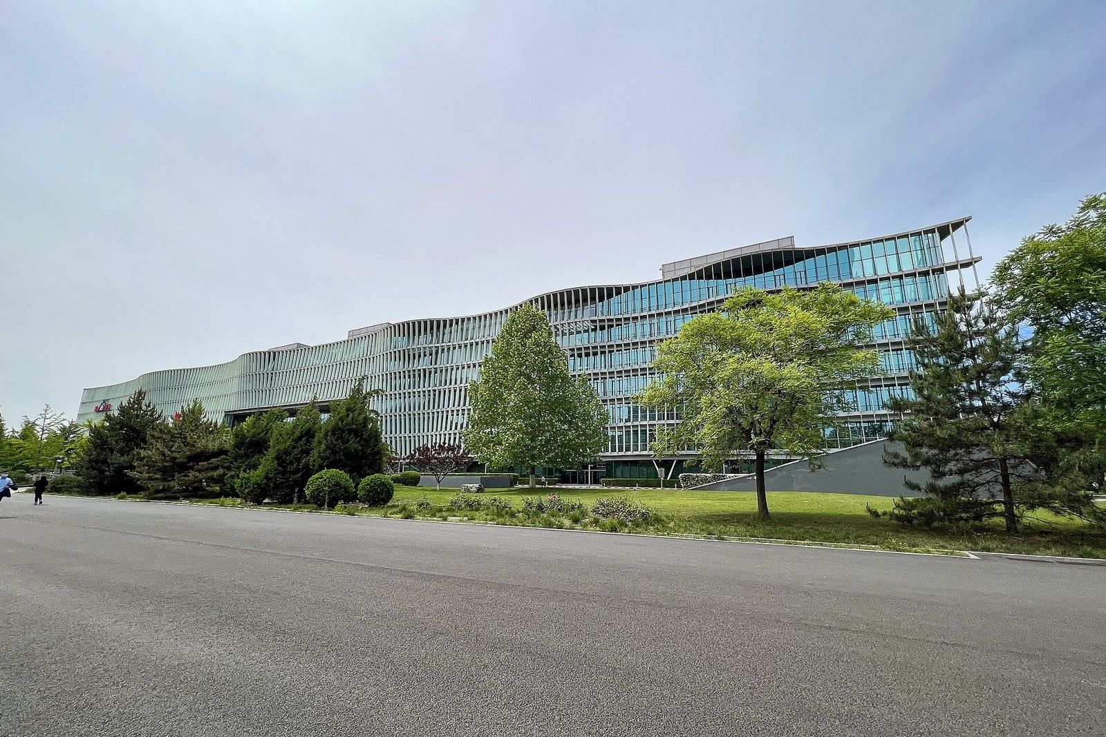 Baidu: Long low glass building behind trees and a wide road