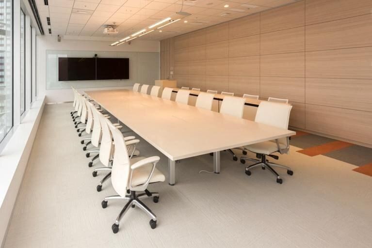 Bandai Namco: Long boardroom table lined with white chairs facing two wall screens