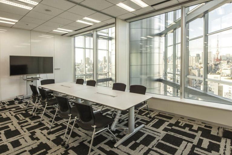 Bandai Namco: Meeting room with a long white table, black chairs, a wall screen and floor-to-ceiling windows