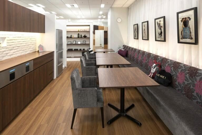 Bandai Namco: Pantry with dark wood cabinets, a long banquette and framed pictures on a white wall
