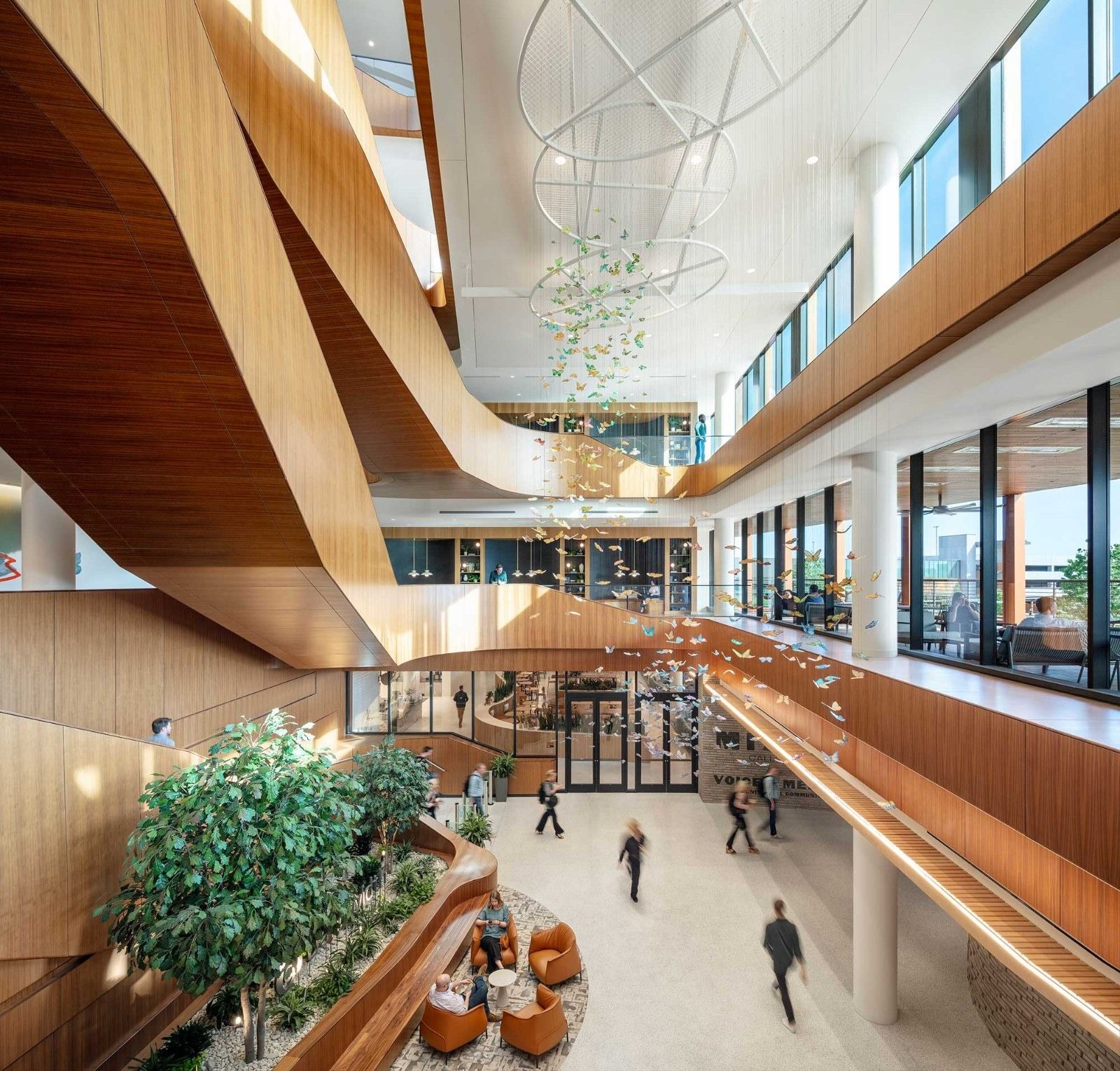 A tall atrium with wooden balconies and trees