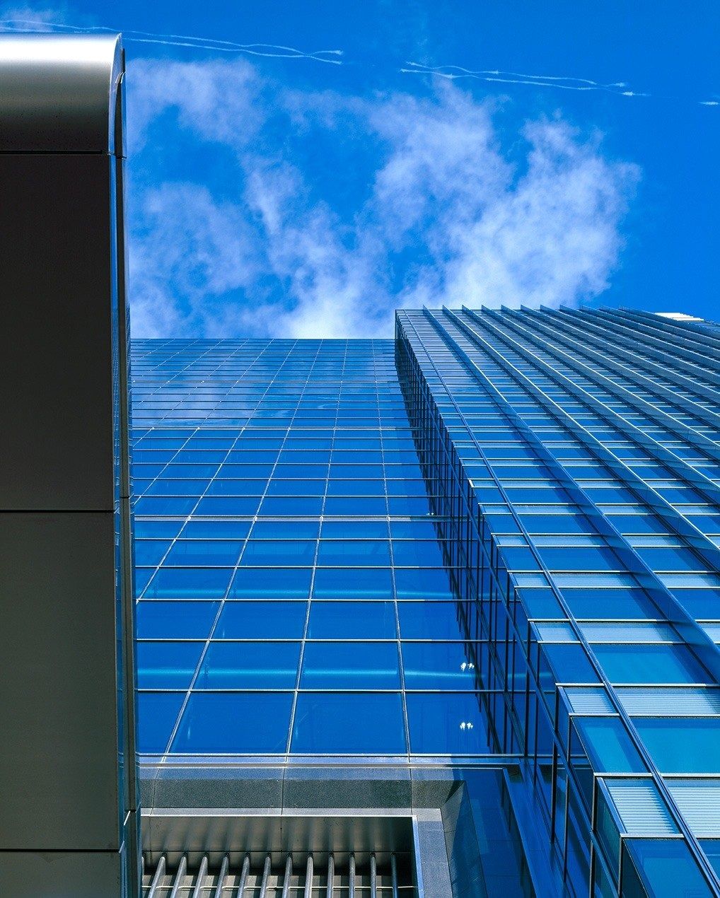 Barclays: Close view of a blue glass curtain wall against clouds