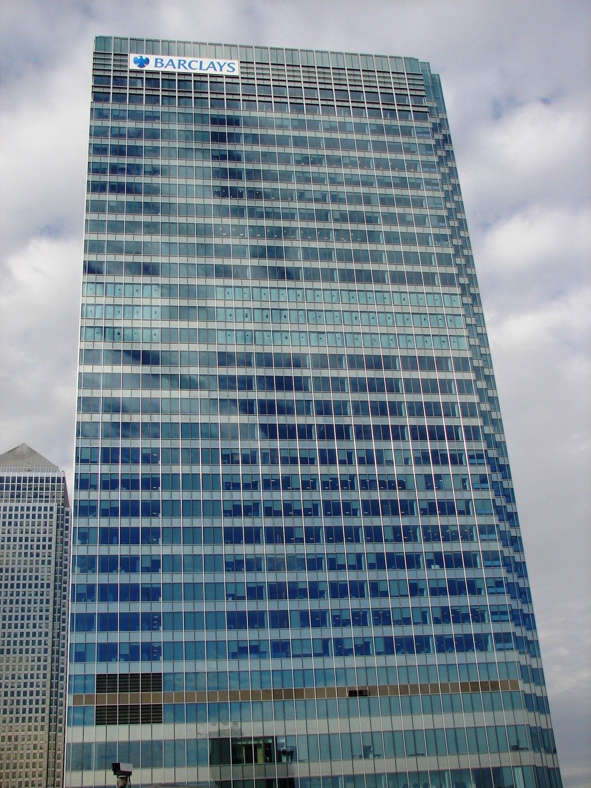 Barclays: Glass tower with a logo at the top under a cloudy sky