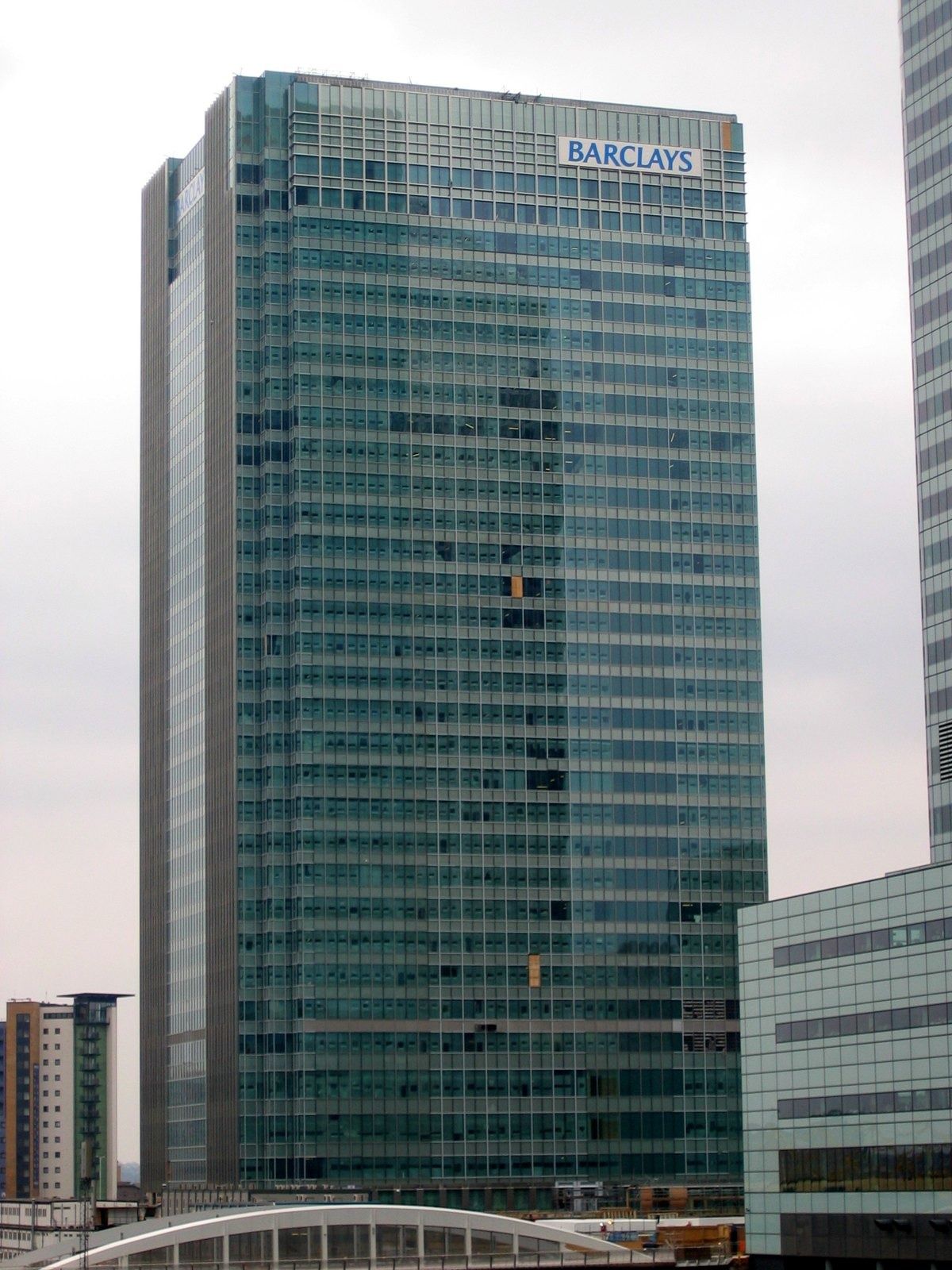 Barclays: Tall glass tower beside a curved roof structure