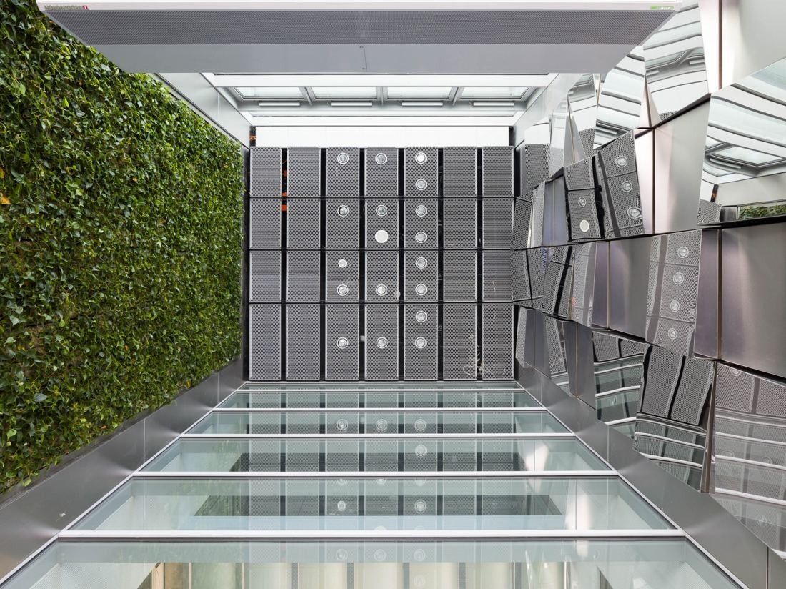 Atrium with a green plant wall, a glass floor and metal facade panels