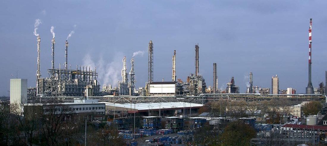 Chemical plants with steam and tall stacks behind a fence