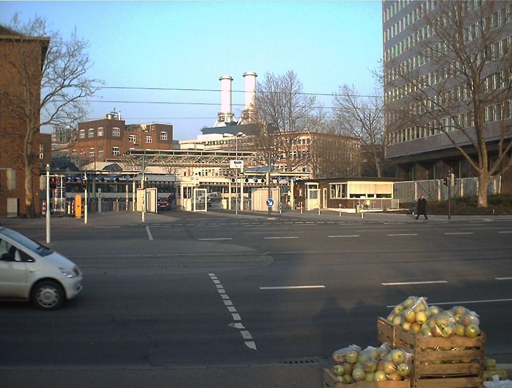Factory gate with brick buildings and a high-rise at the edge of the picture