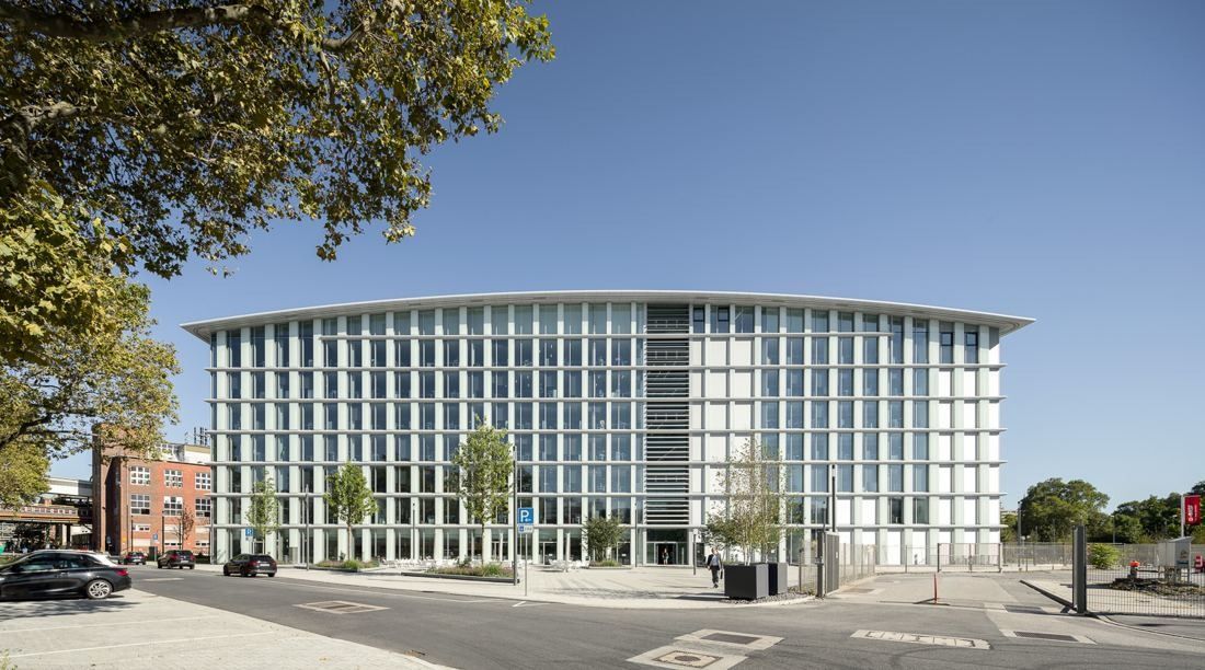 Flat glass facade of an office block with trees in the foreground