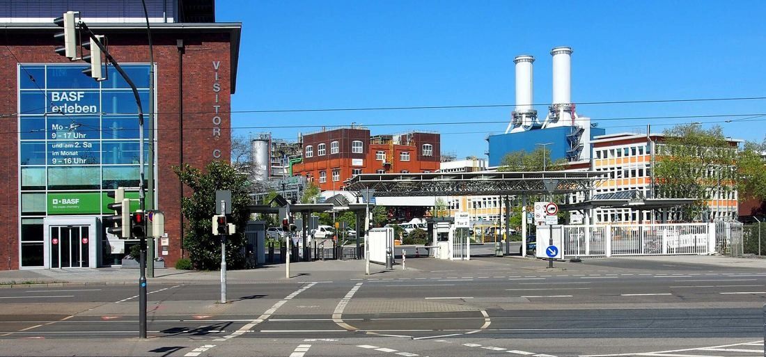 Glass entrance of a brick building with factory chimneys behind