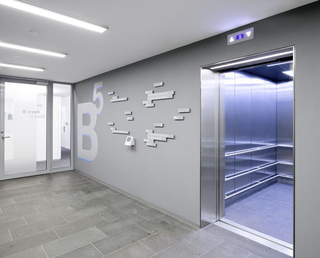 Grey elevator lobby with an open lift and a wall graphic