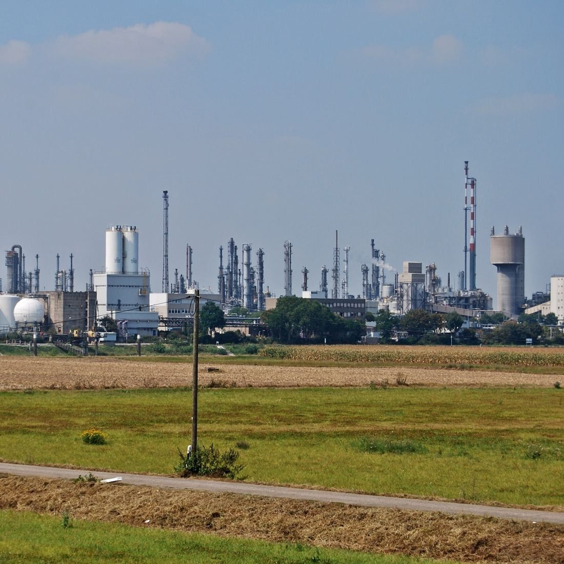 Industrial plants and towers seen across a field