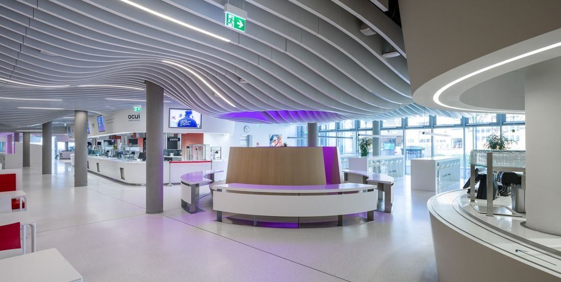 Open area with a round counter under a curving white slatted ceiling