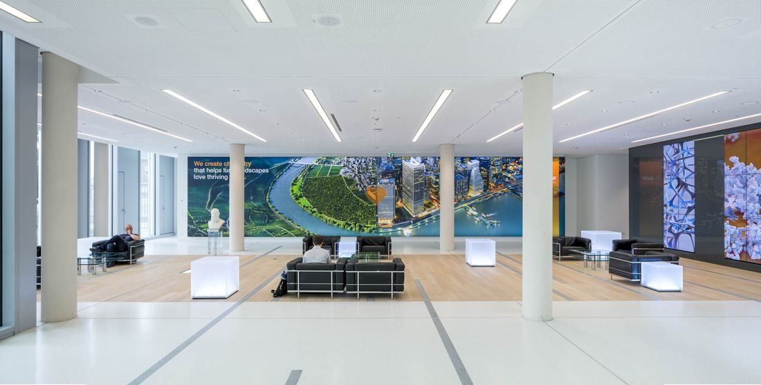 Open lounge with black sofas and large screens showing images