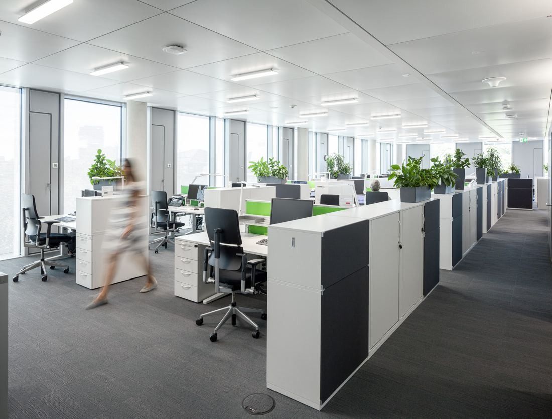Rows of desks separated by white cabinets with plants on top