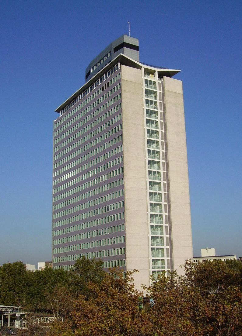 Tall slender office high-rise with a pale facade against a blue sky