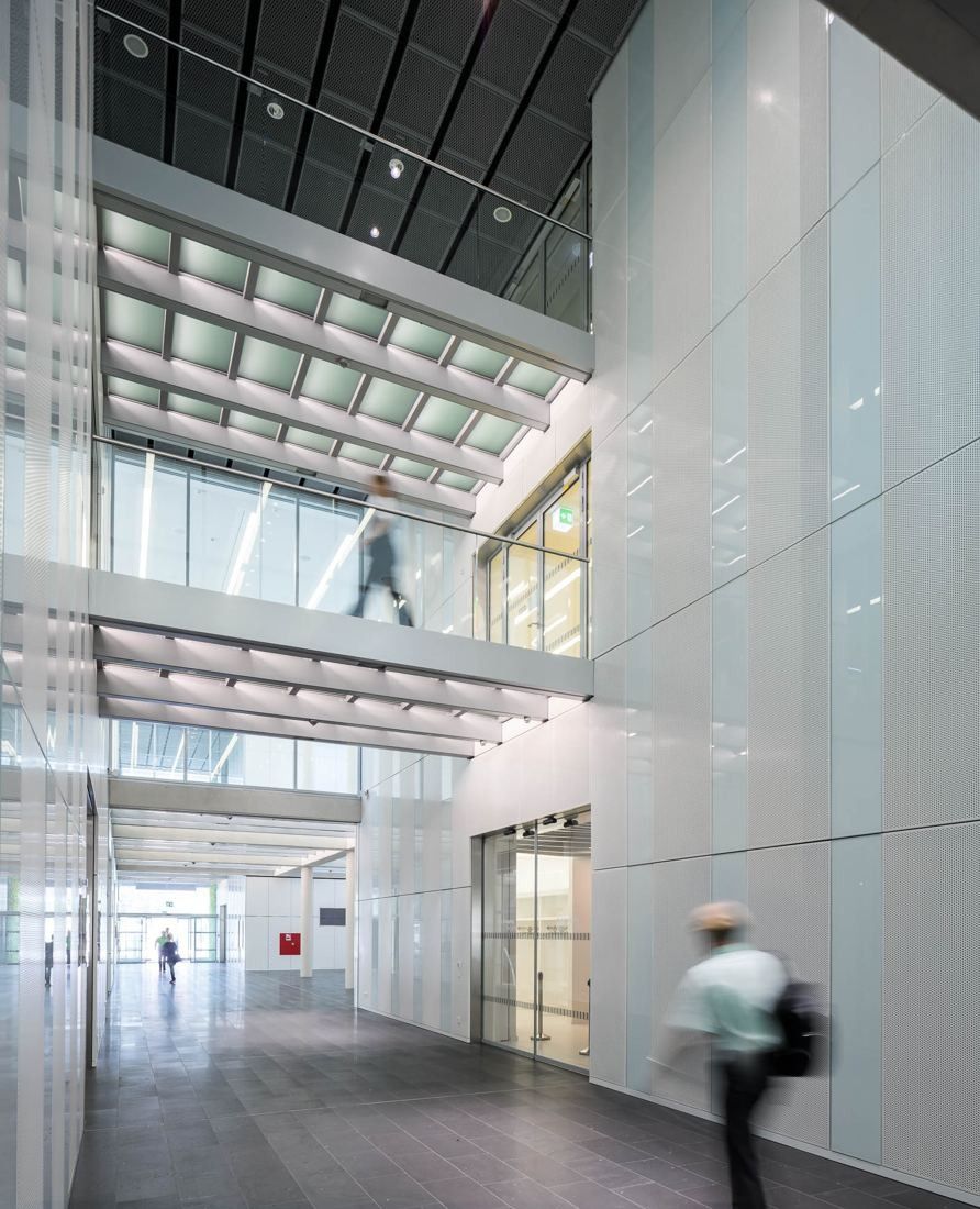Tall white atrium with a bridge and a person walking across it