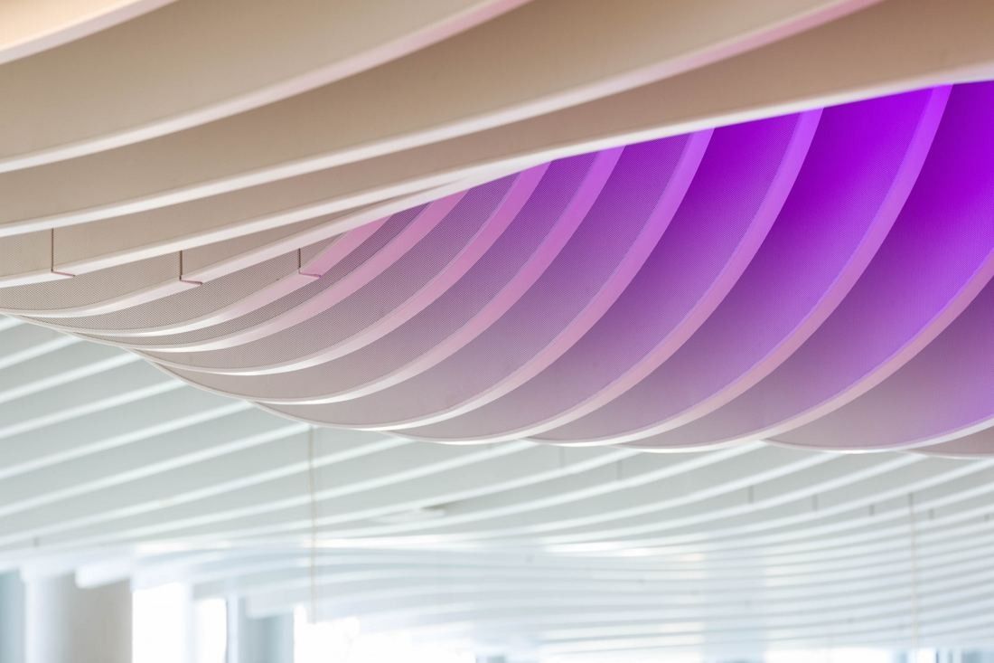 Wave-shaped white ceiling slats lit with purple light