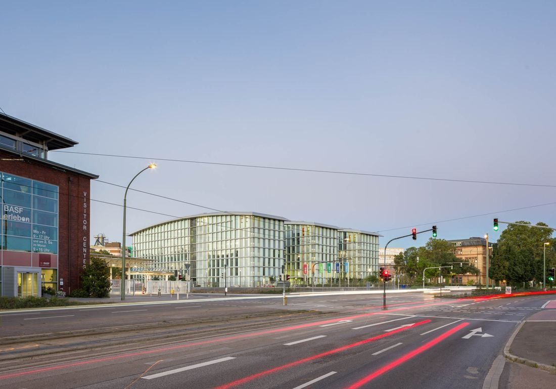 Wide street with light trails leading toward a long glass office building