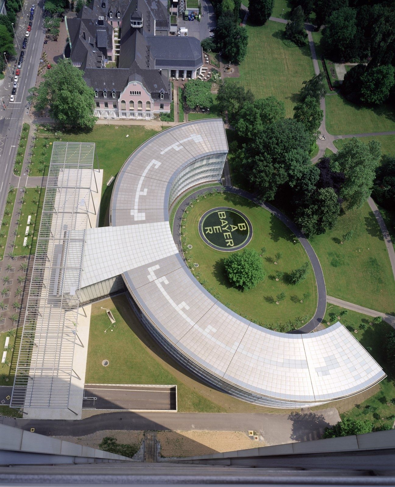 Bayer: Aerial view of a semicircular glass building in a park